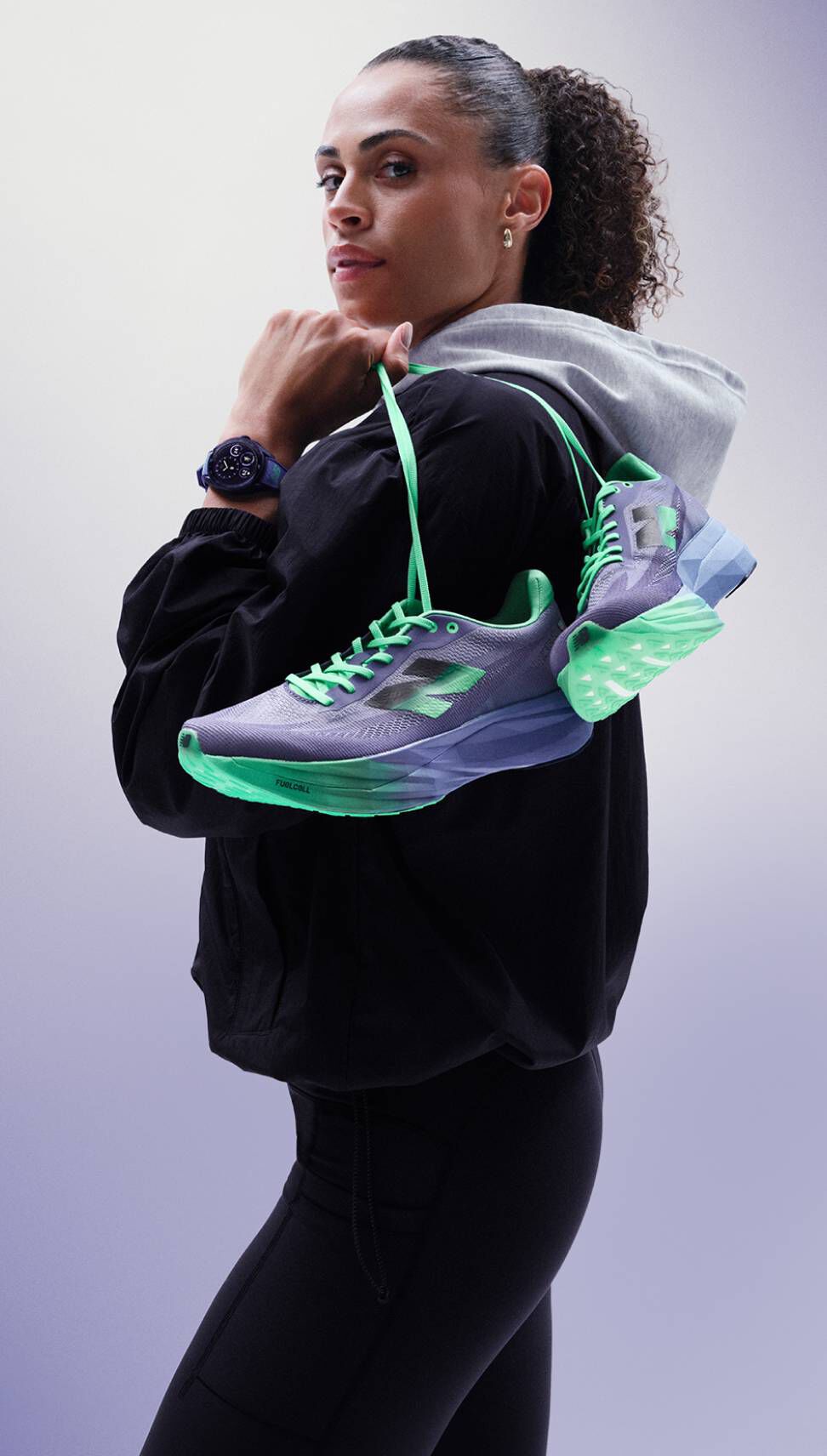  Sydney McLaughlin-Levrone holding a pair of shoes over her shoulder and looking towards the viewer. 