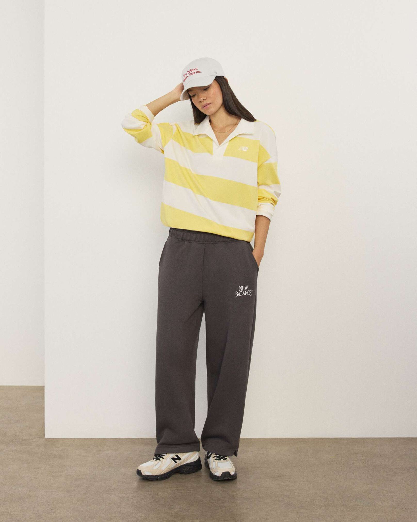 A woman wearing New Balance standing in front a white wall.