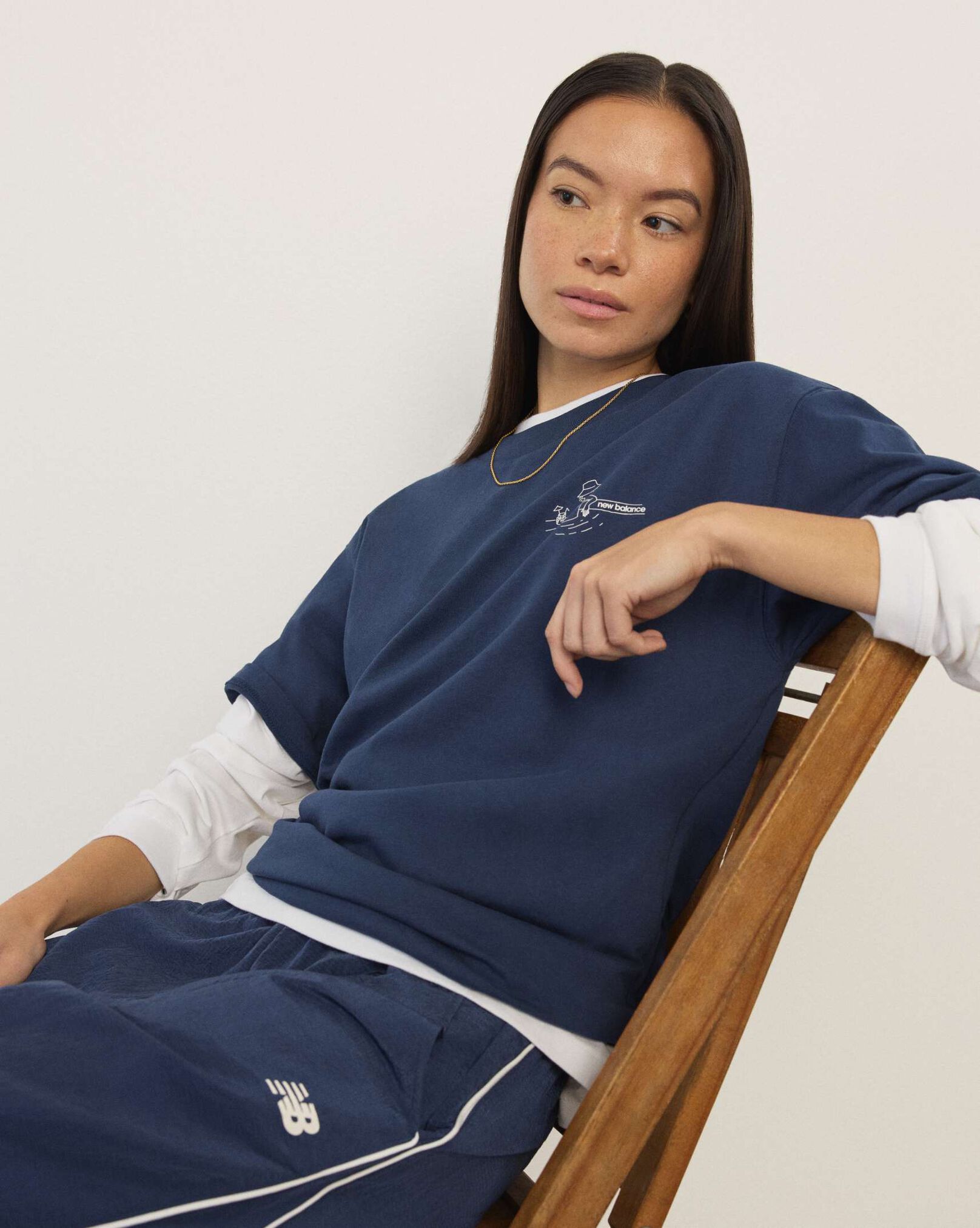 A woman wearing New Balance standing in front a white wall.