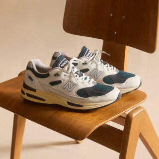 A pair of New Balance Made in UK sneakers in front of a rabbit in a brown textured studio environment. 